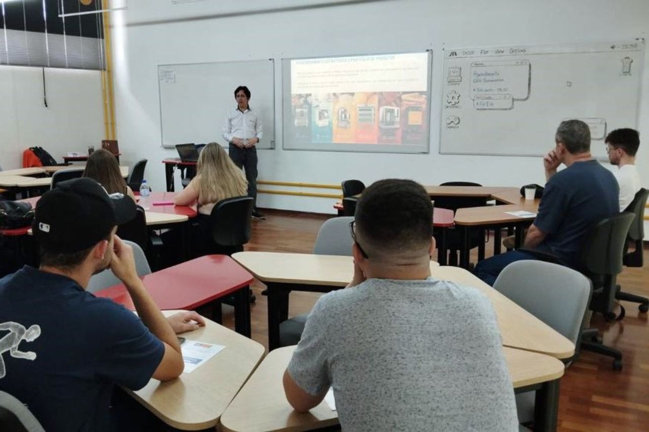 Um homem está fazendo uma apresentação para um grupo de pessoas em uma sala de aula