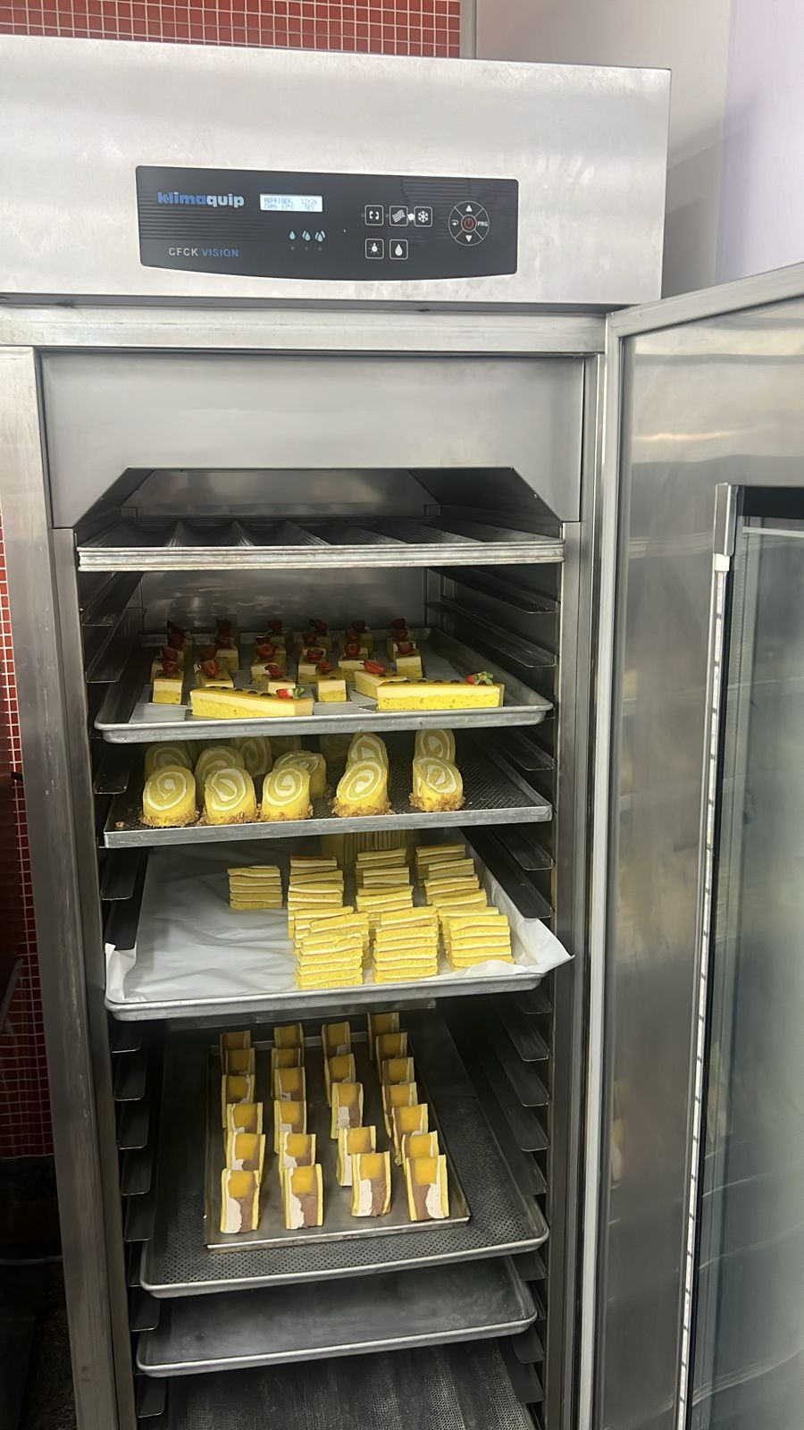 Uma geladeira de aço inoxidável cheia de bandejas de comida.