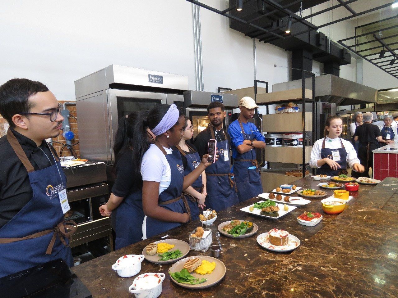 Um grupo de pessoas está de pé ao redor de uma mesa com pratos de comida sobre ela.
