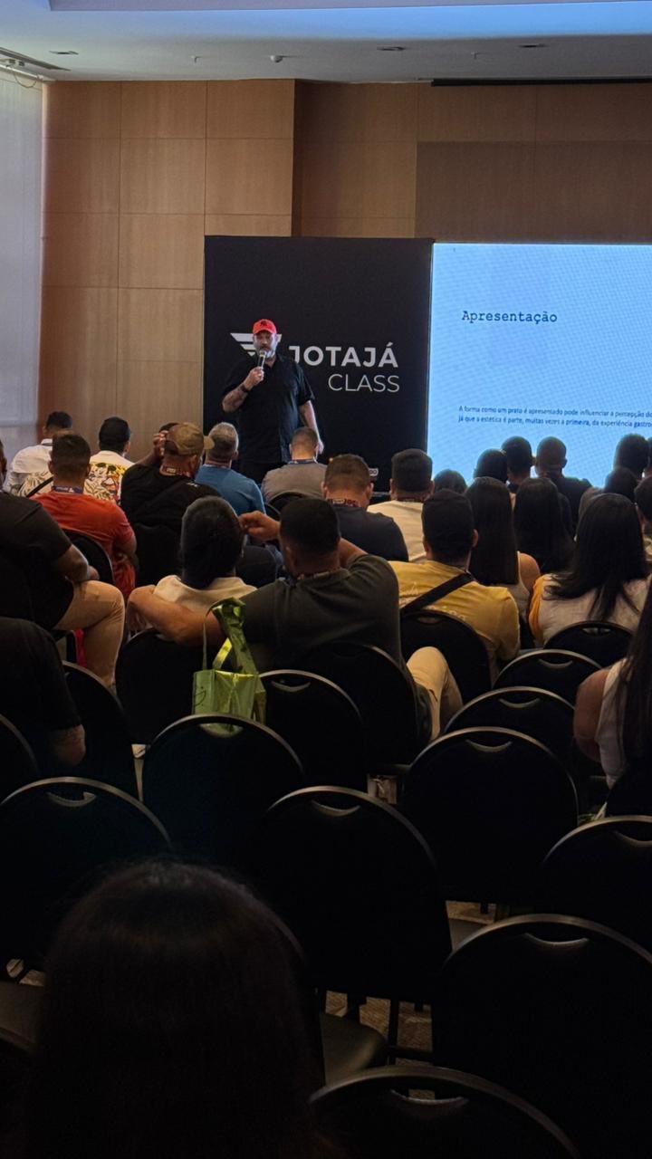 Um homem está fazendo uma apresentação para um grande grupo de pessoas em uma sala de conferências.