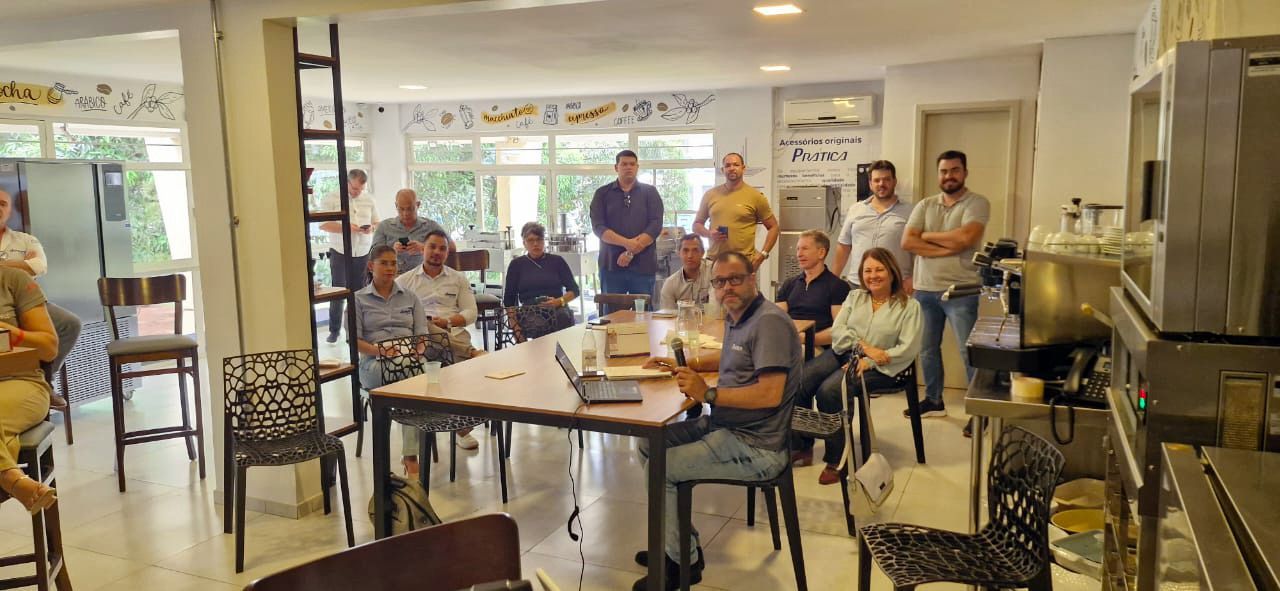 Um grupo de pessoas está sentado ao redor de uma mesa em uma sala.