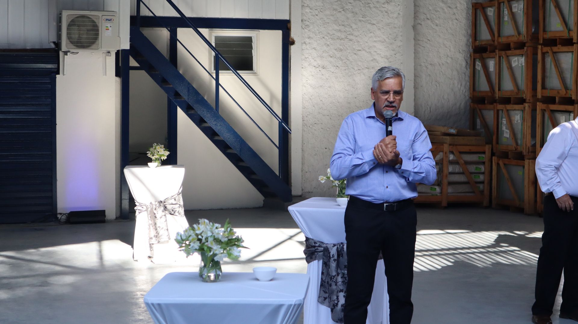 Um homem está de pé em frente a uma mesa com um microfone na mão.