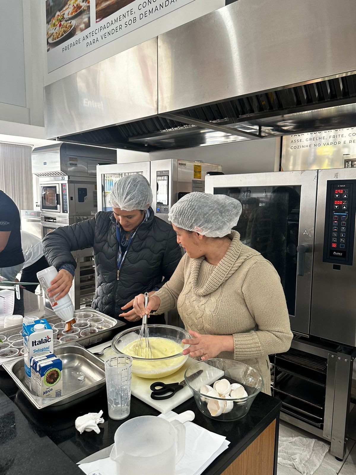 Duas mulheres estão em uma cozinha preparando comida.