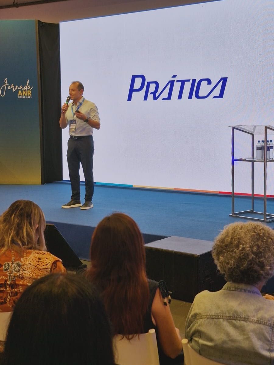 Um homem está fazendo uma apresentação em frente a uma tela que diz prática