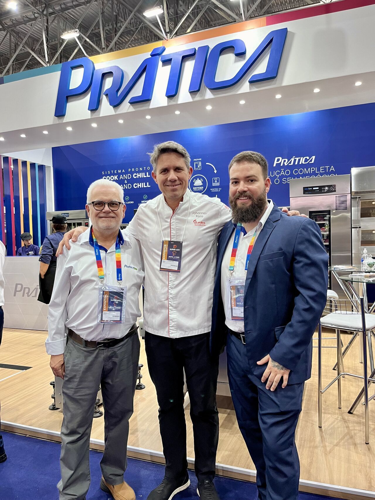 Três homens estão posando para uma foto em frente a uma placa de prática.