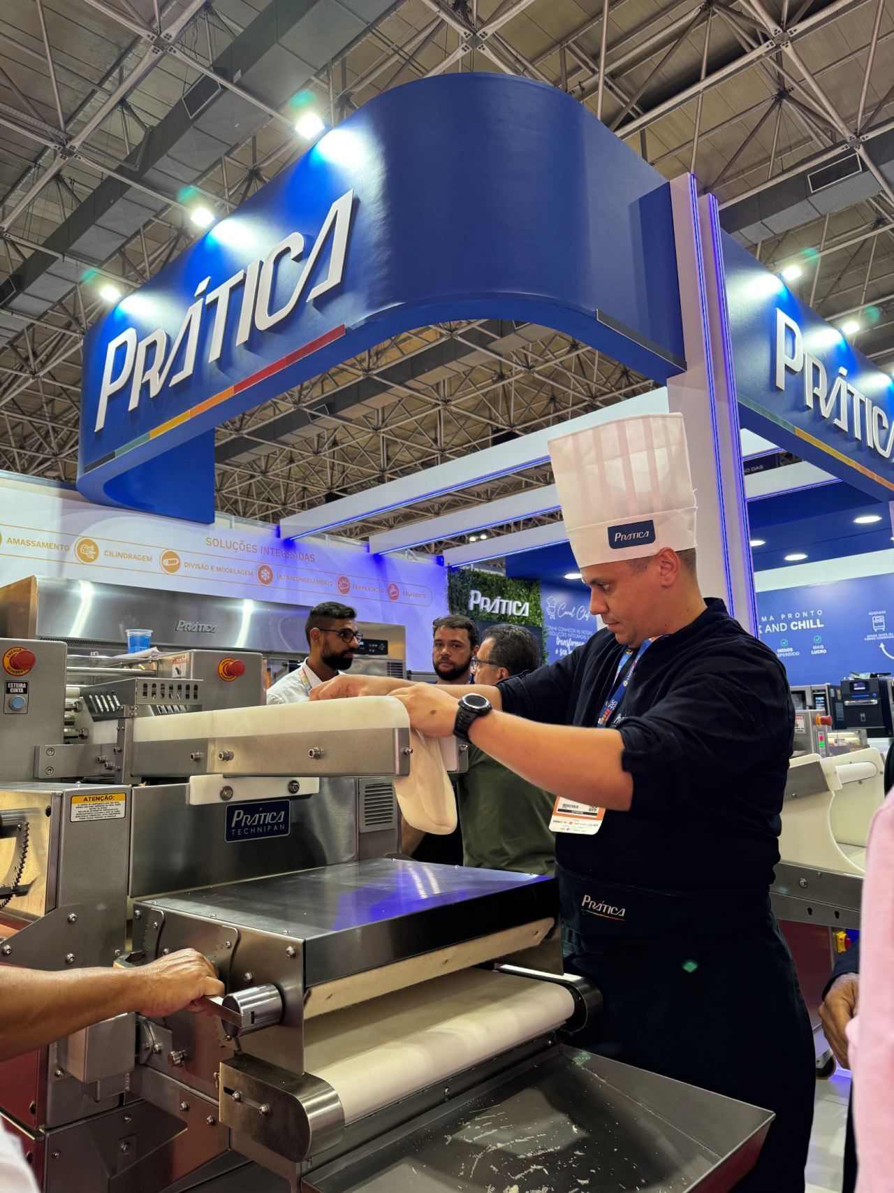 Um homem com chapéu de chef está trabalhando em uma máquina.