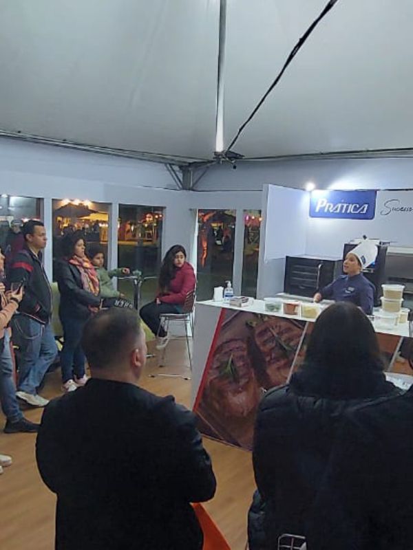 Um grupo de pessoas está reunido em uma sala com uma placa que diz