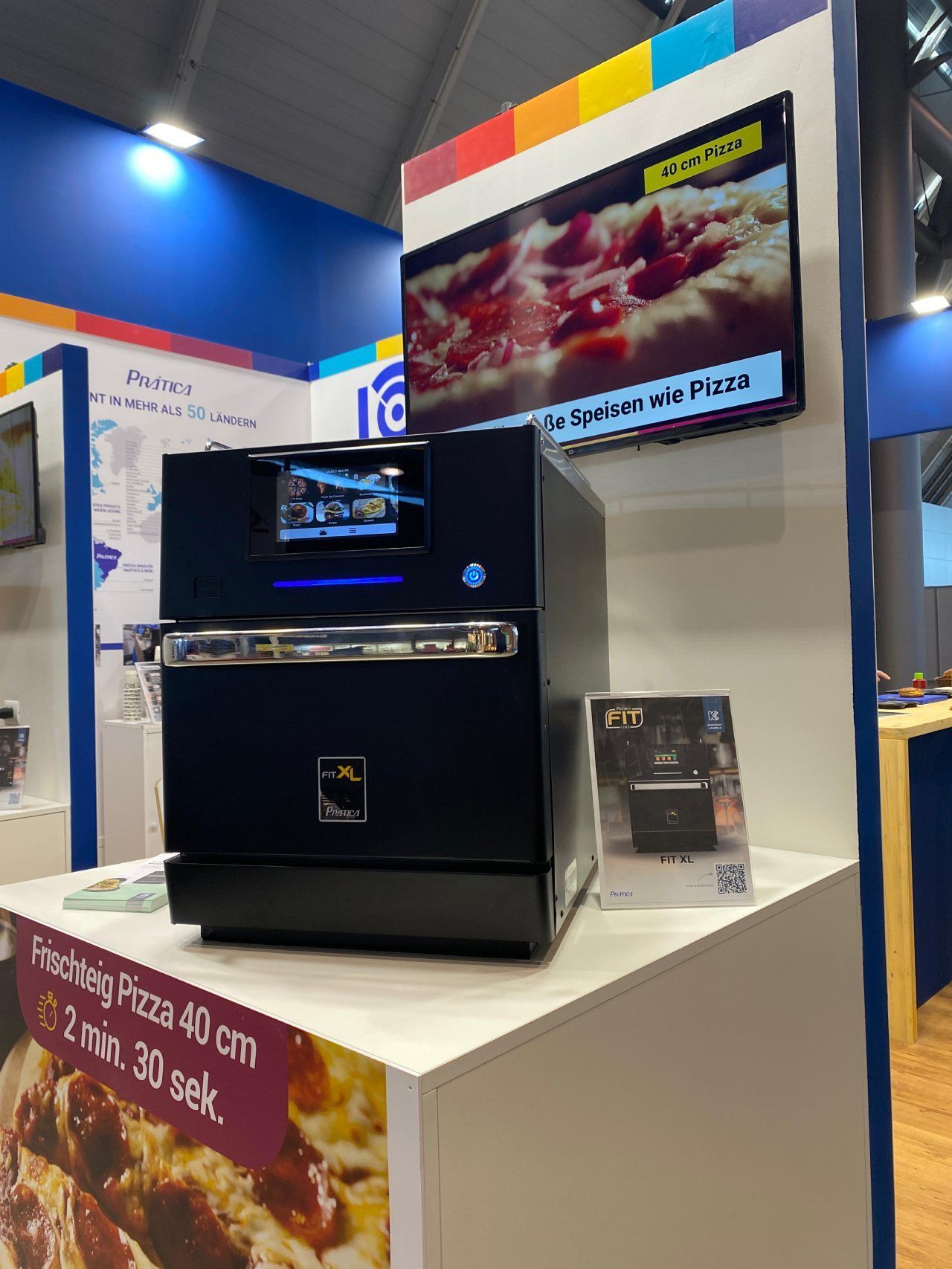 Um forno de pizza está sobre uma mesa em frente a uma TV.