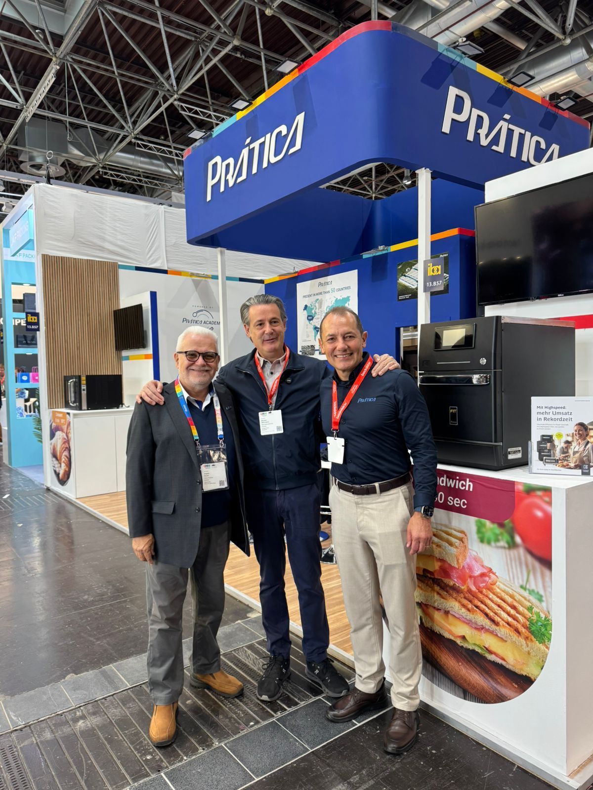 Três homens estão posando para uma foto em frente a uma barraca de comida.