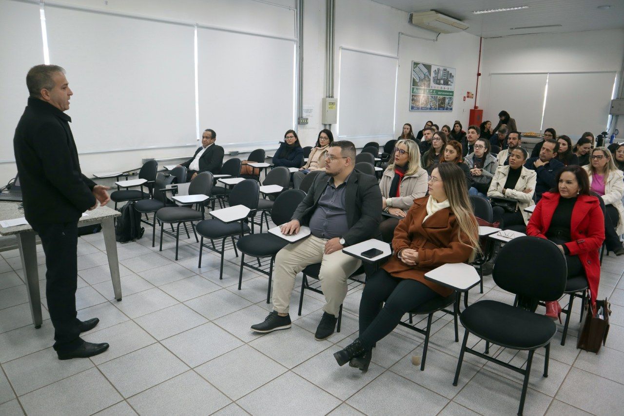 Um homem está fazendo uma apresentação para um grupo de pessoas sentadas em cadeiras.