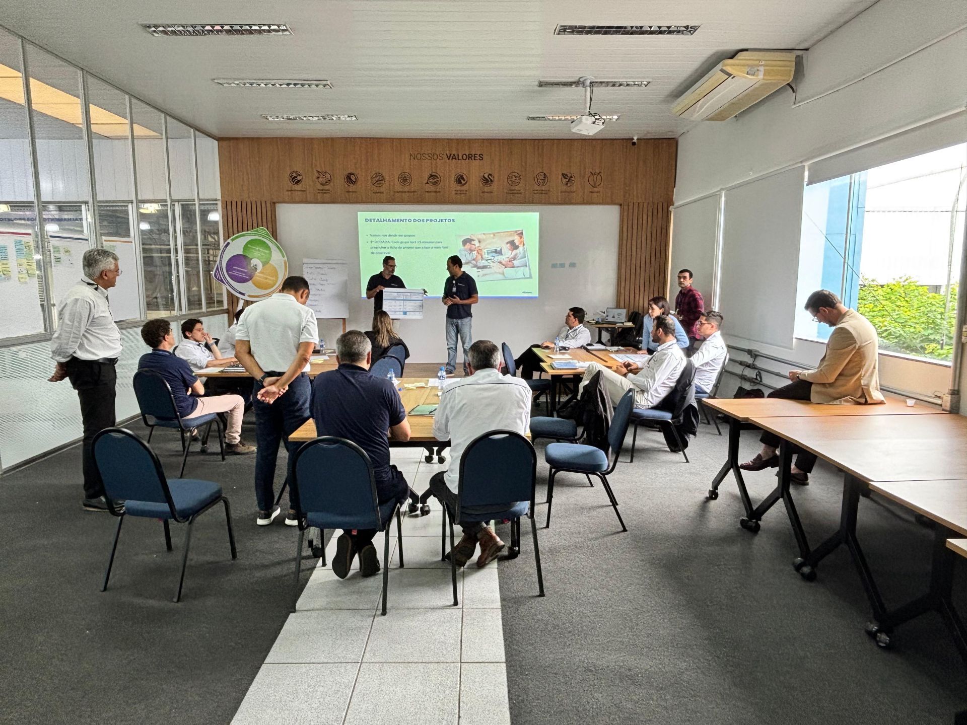 Um grupo de pessoas está sentado em mesas em uma sala.