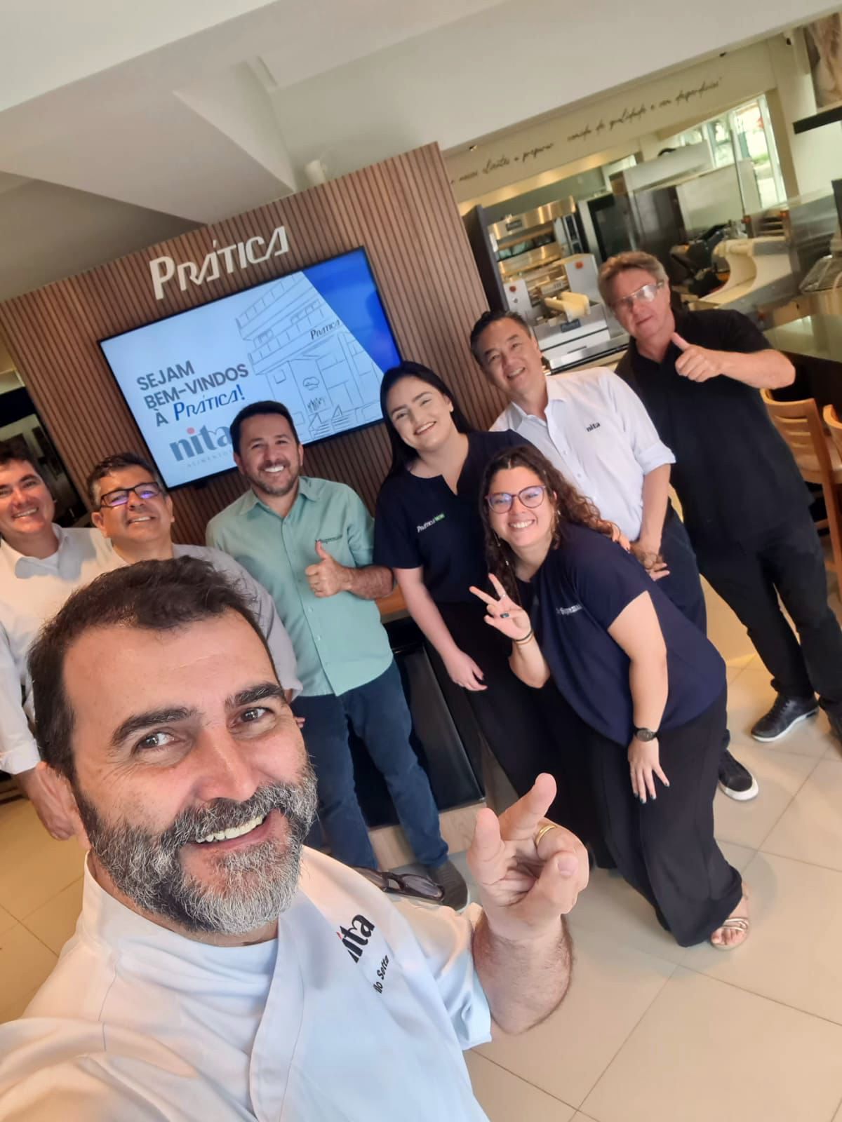 Um grupo de pessoas está posando para uma foto em frente a uma placa que diz pastics