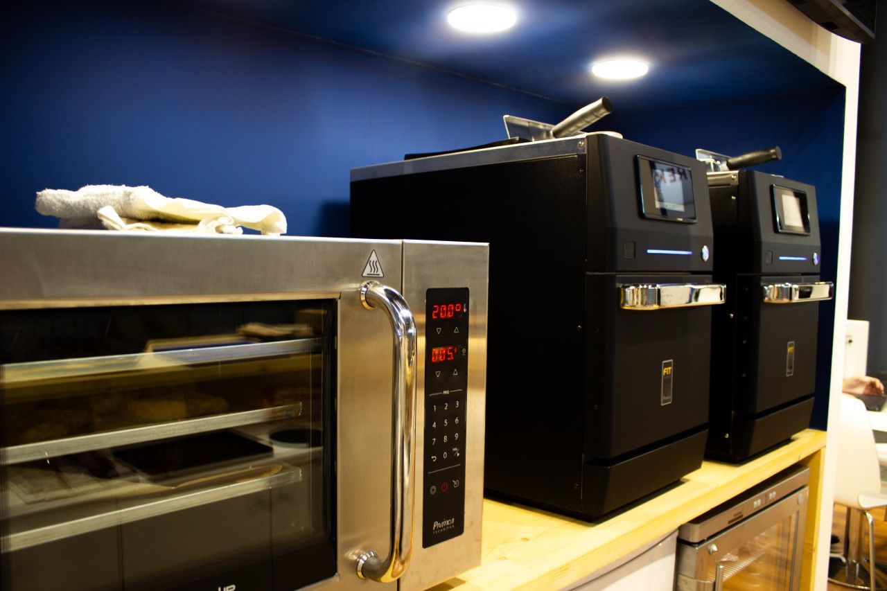 Três fornos de micro-ondas estão alinhados sobre um balcão de madeira.