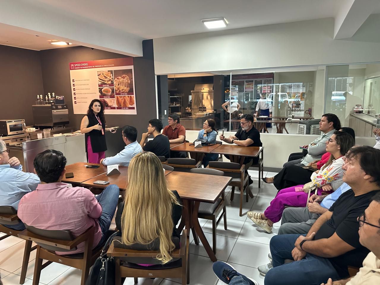 Um grupo de pessoas está sentado em mesas em uma sala.