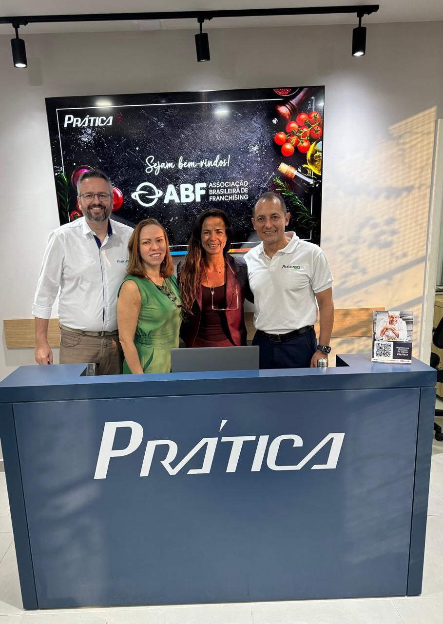 Um grupo de pessoas está posando para uma foto em frente a uma placa de prática.