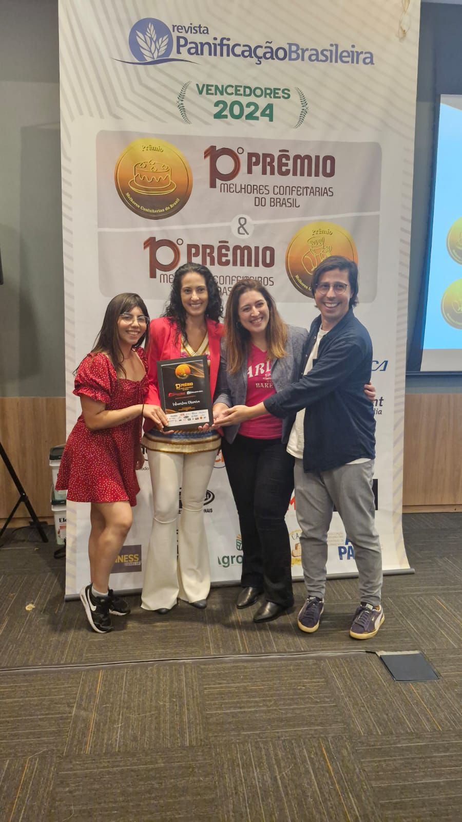 Um grupo de mulheres estão de pé, uma ao lado da outra, segurando um troféu.