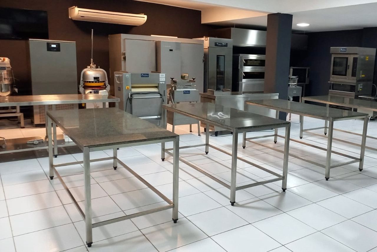 Uma cozinha com mesas e eletrodomésticos de aço inoxidável