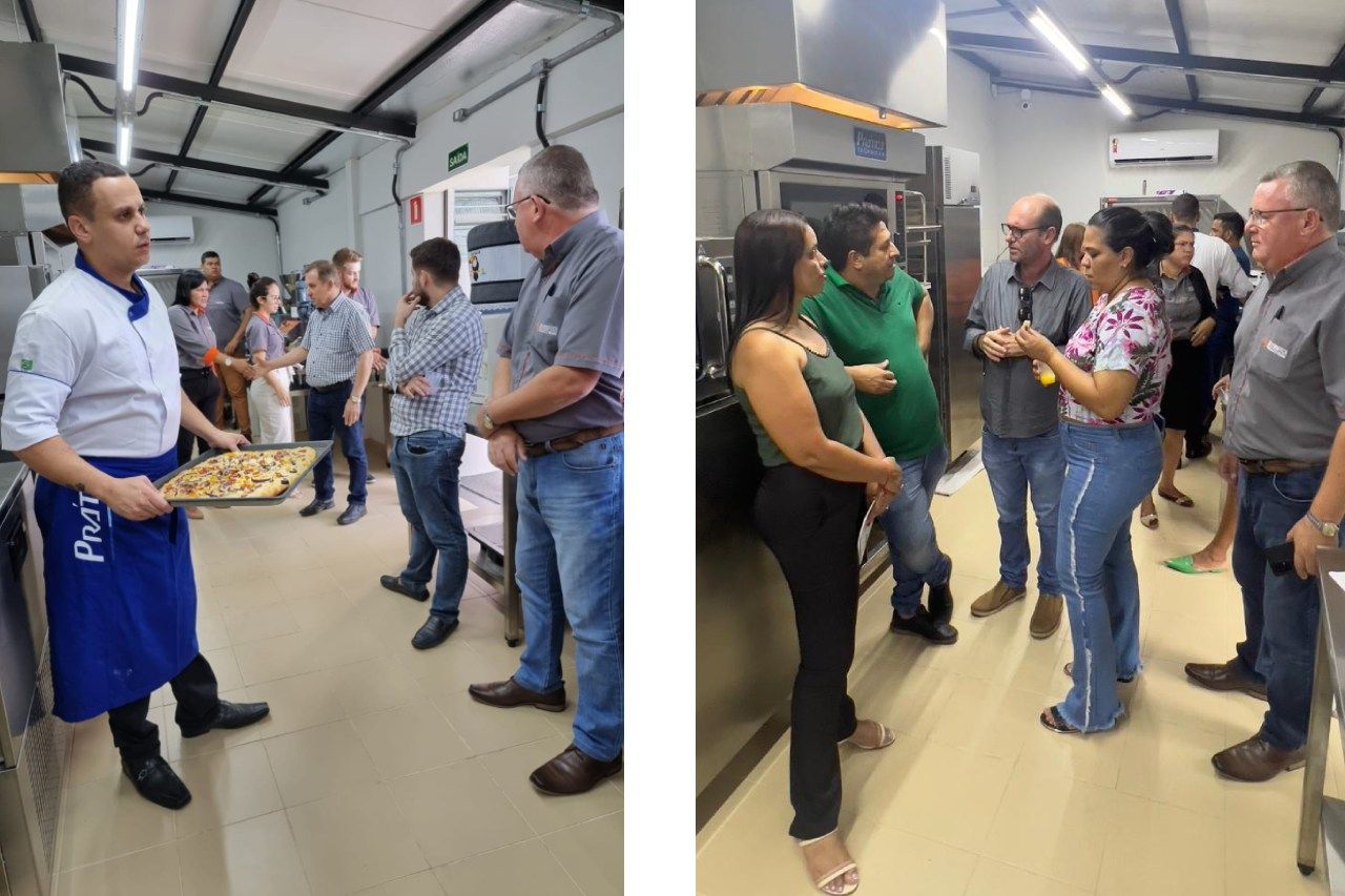 Um homem está segurando uma bandeja de pizza e conversando com um grupo de pessoas.