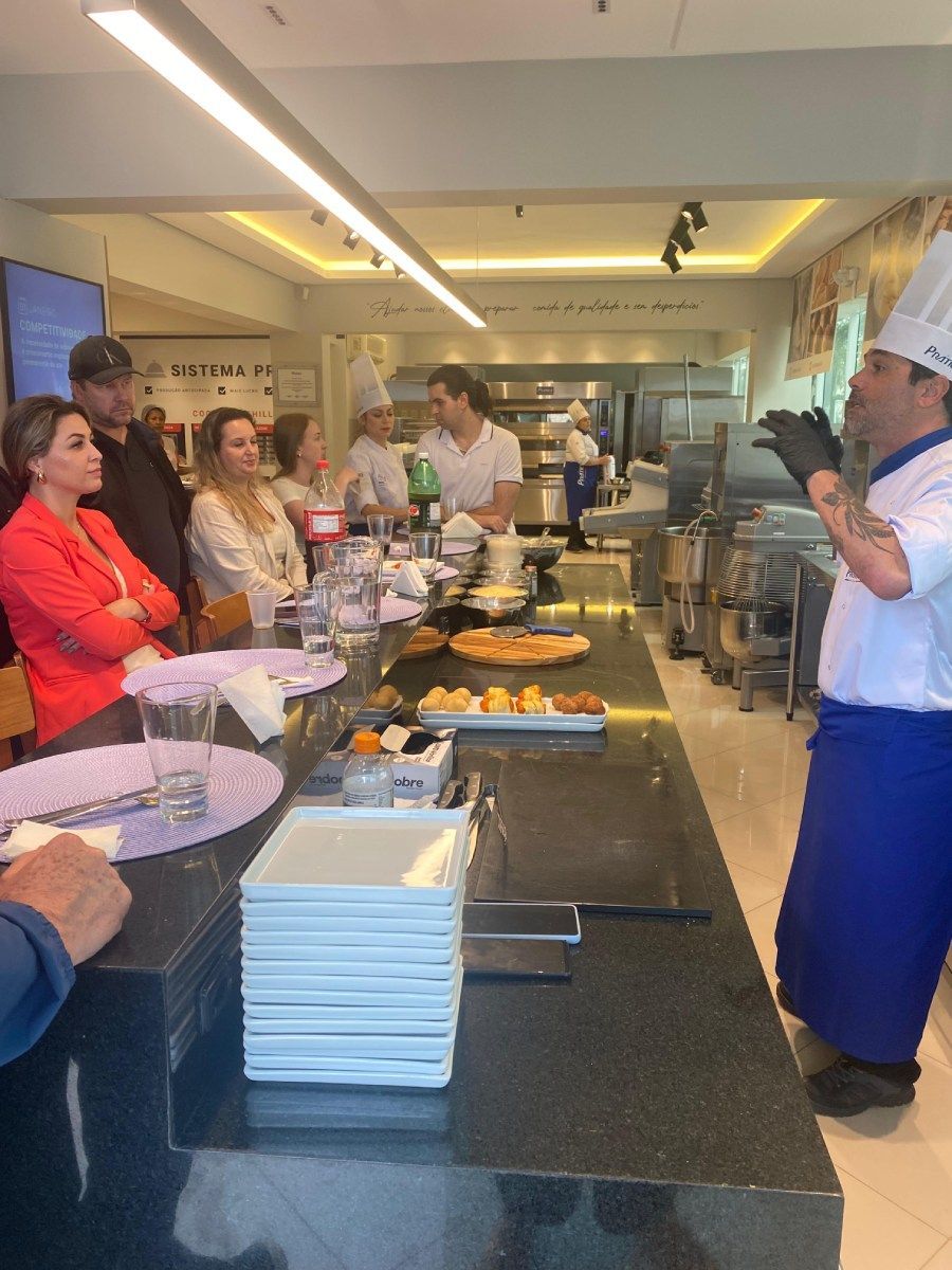 Um chef está fazendo uma apresentação para um grupo de pessoas em uma cozinha.