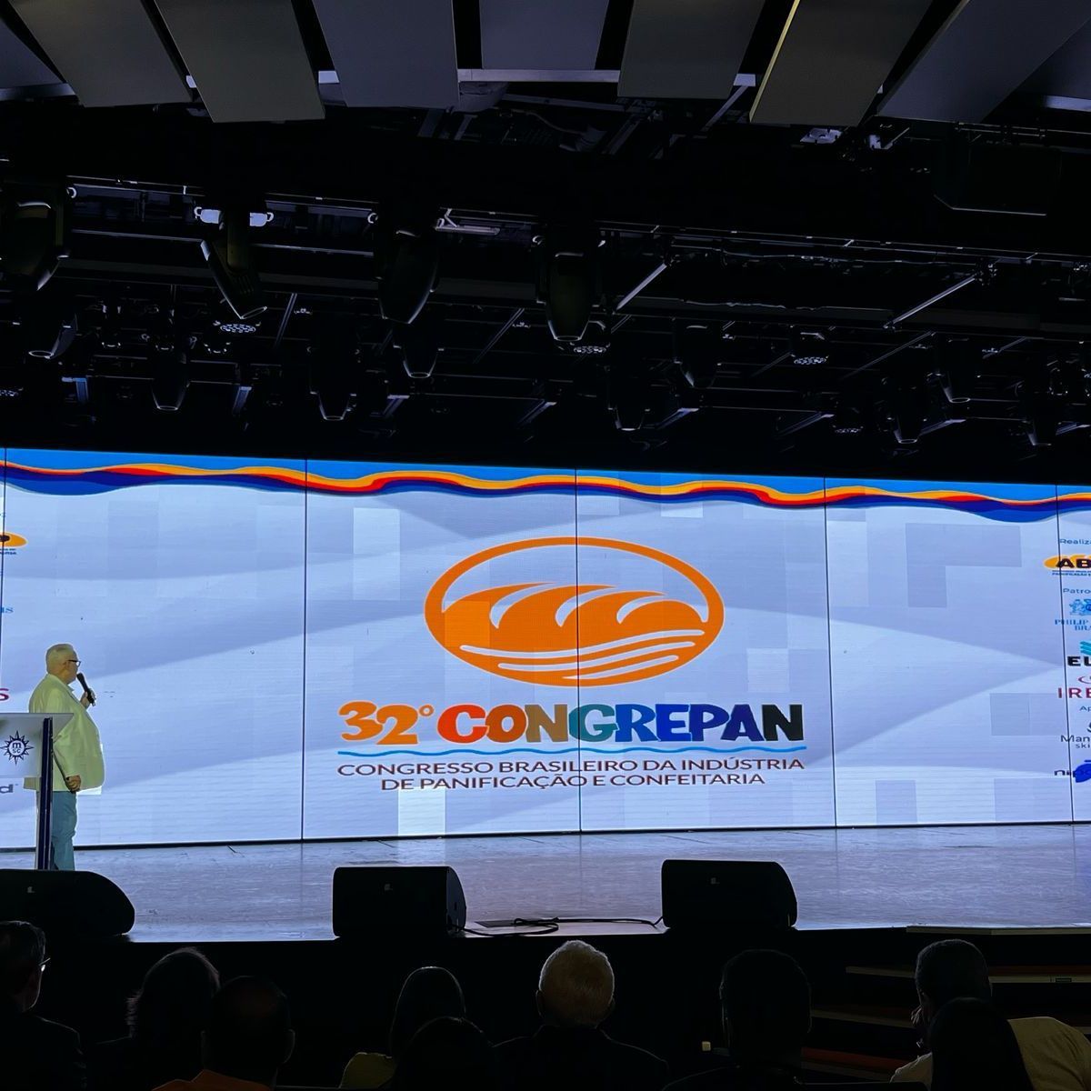 Uma mulher está em frente a uma tela grande que diz 32 congressistas