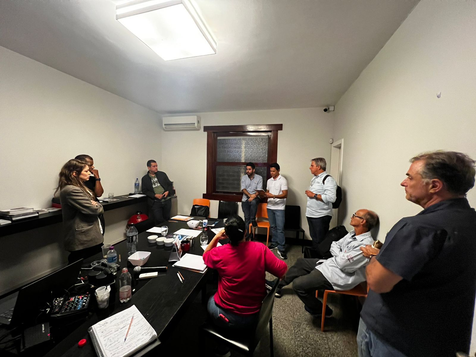 Um grupo de pessoas em pé ao redor de uma mesa em uma sala