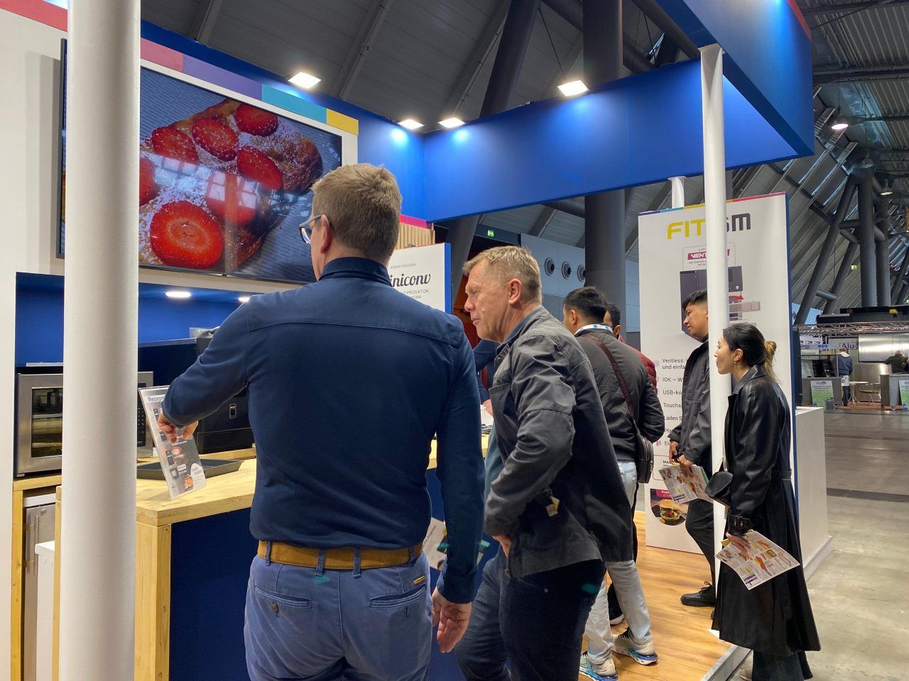 Um grupo de pessoas está em volta de um estande em uma convenção.