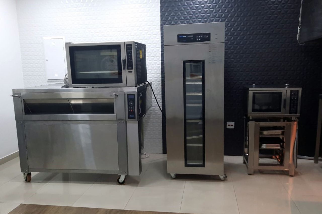 Três fornos de aço inoxidável estão lado a lado em uma sala.