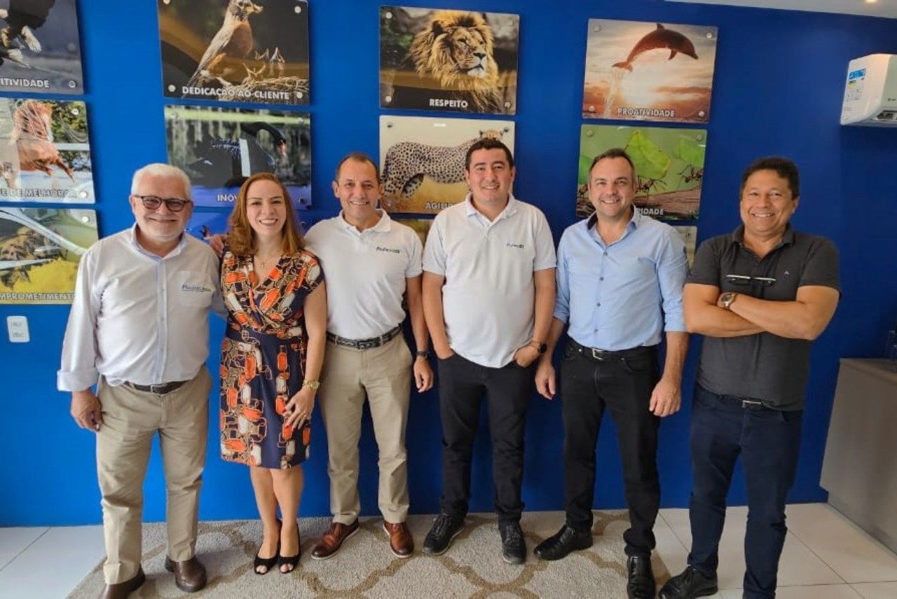 Um grupo de pessoas está posando para uma foto em frente a uma parede azul.