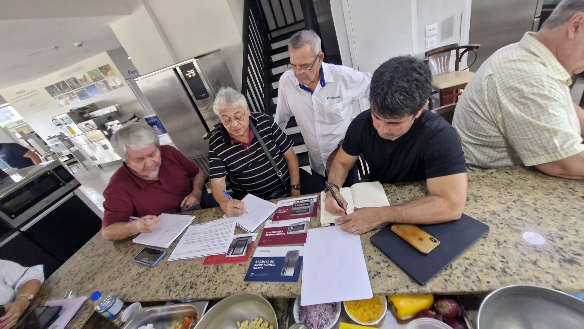 Um grupo de homens está sentado à mesa na cozinha.