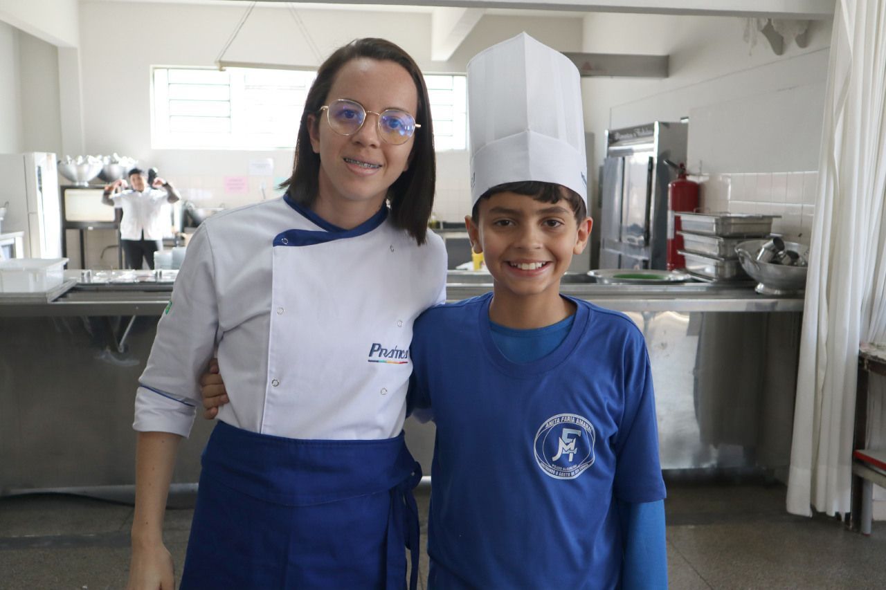 Uma mulher e um menino estão posando para uma foto em uma cozinha