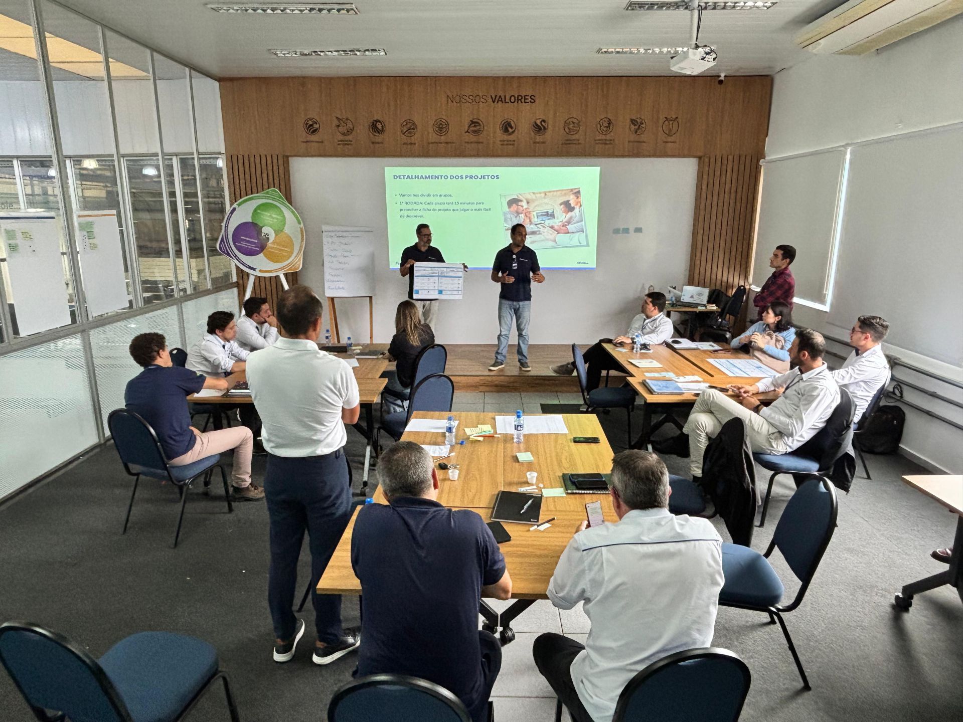 Um grupo de pessoas está sentado ao redor de uma mesa em uma sala de conferências.