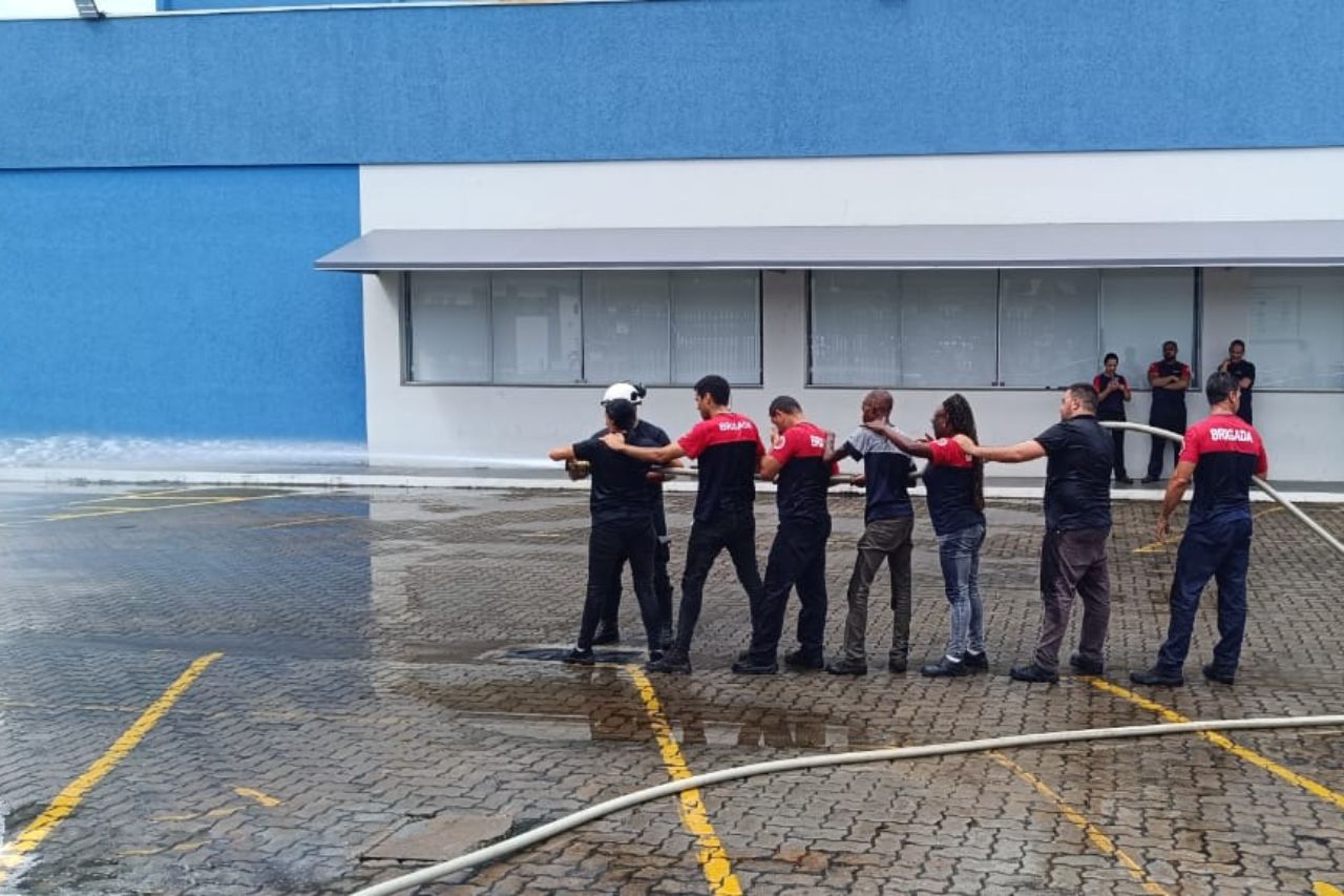 Bombeiros praticam técnicas de combate a incêndio com mangueira ao ar livre.