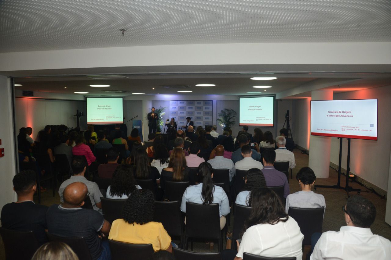 Um grande grupo de pessoas está sentado em frente a uma tela grande