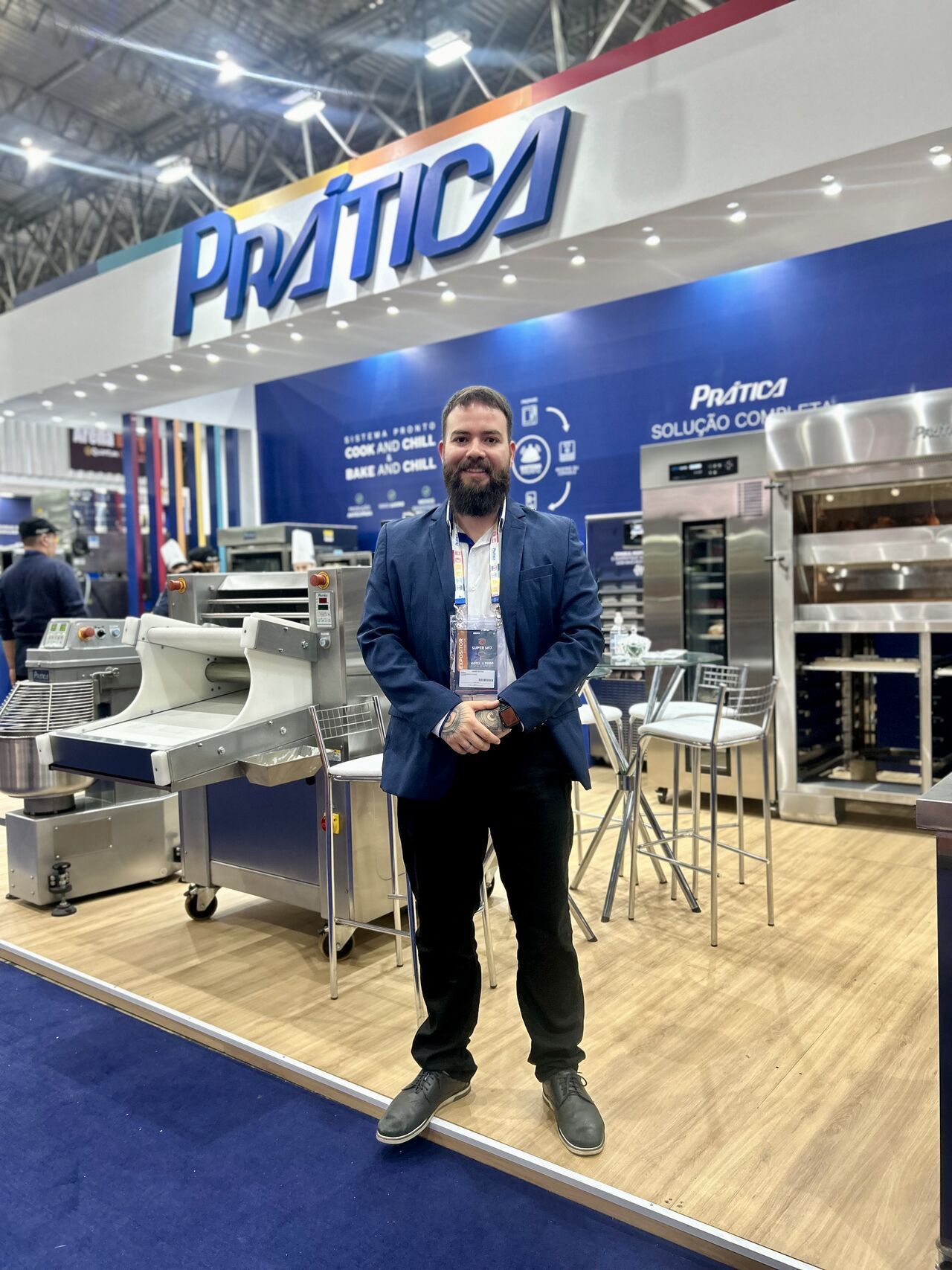 Um homem de terno está parado em frente a um estande em uma convenção.