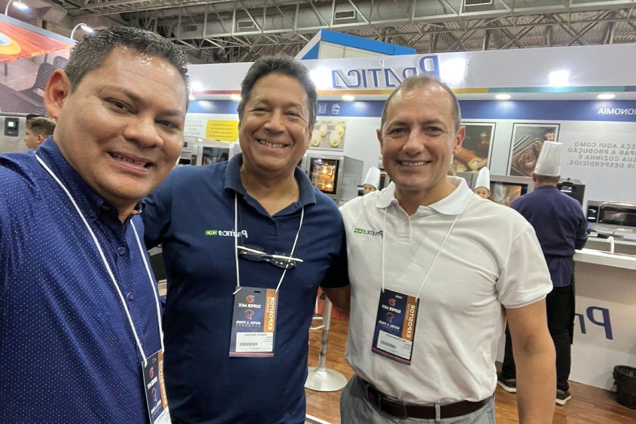 Três homens estão posando para uma foto em uma convenção.