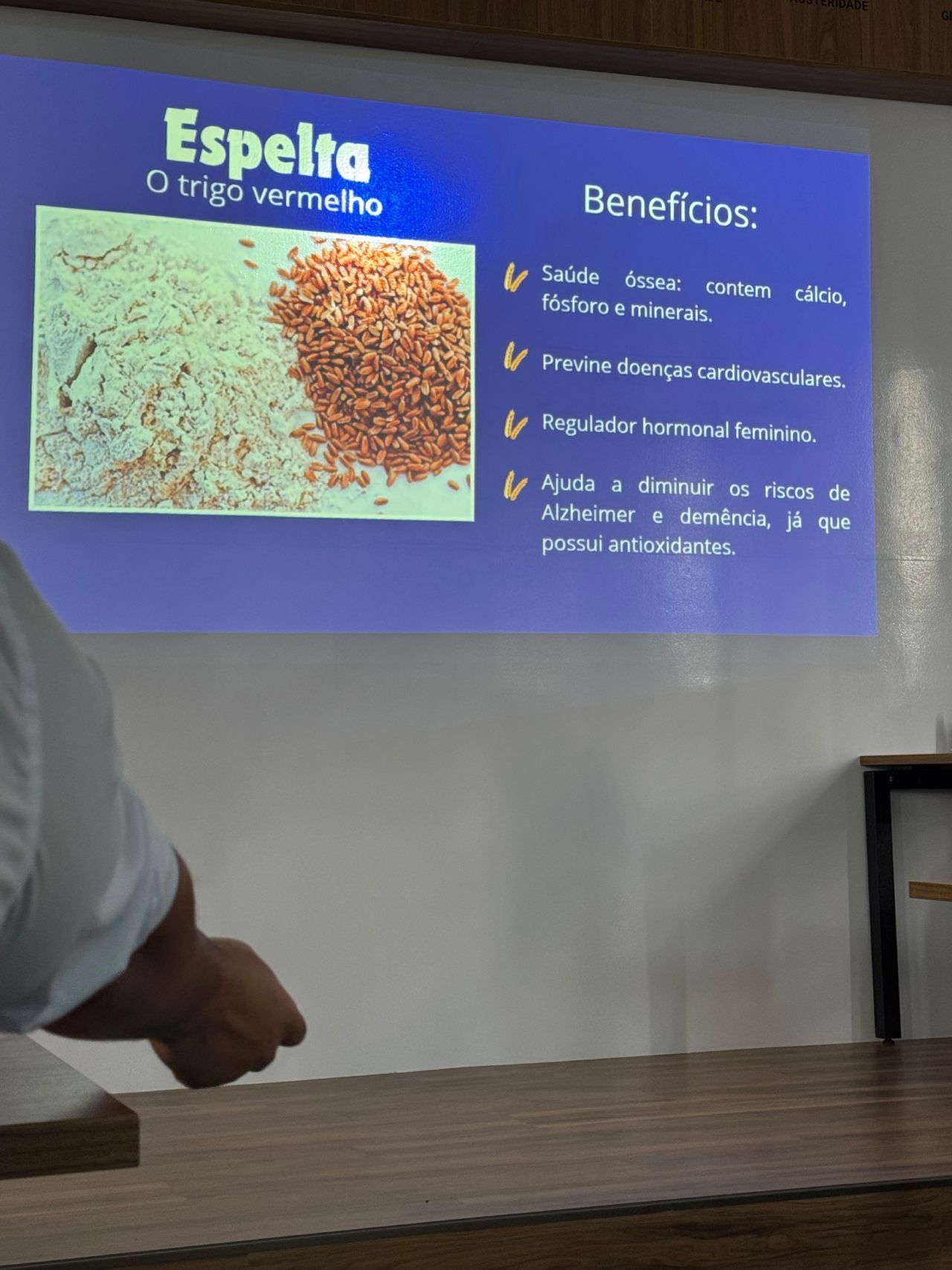 Um homem está em frente a uma tela de projetor que diz espelta