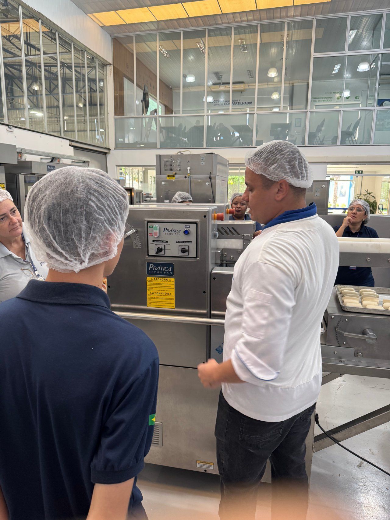 Um homem usando uma rede de cabelo está conversando com outro homem na cozinha.