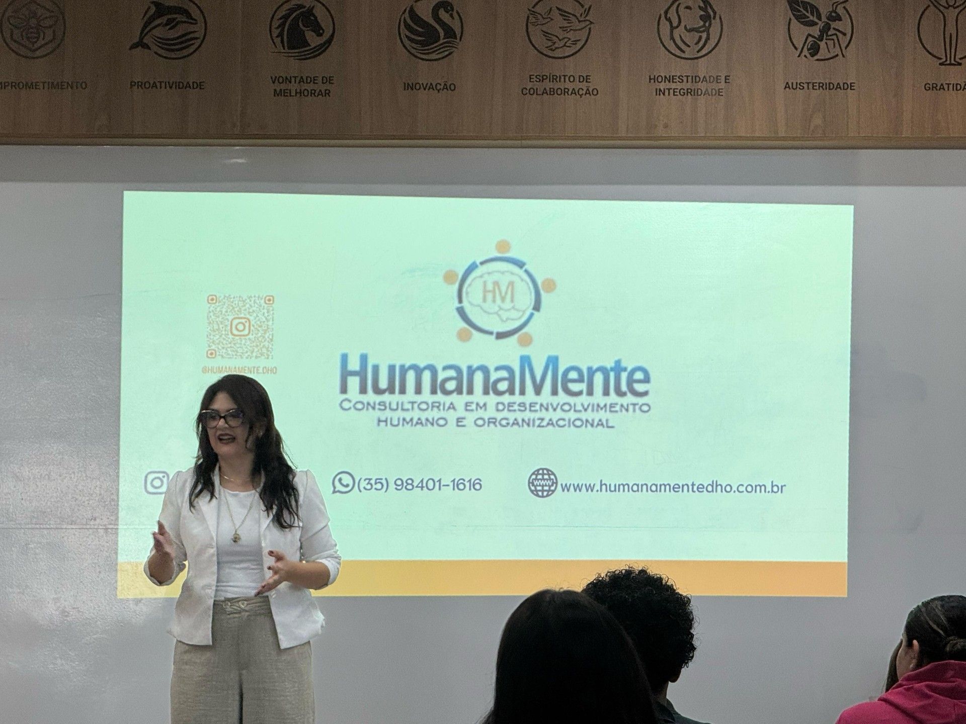 Uma mulher está fazendo uma apresentação em frente a uma tela grande.