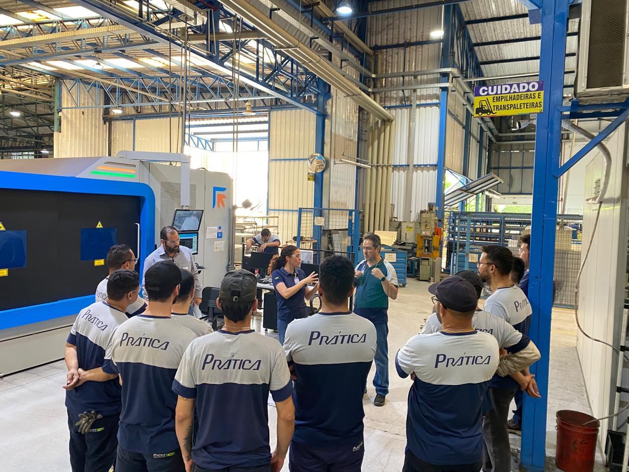 Um grupo de pessoas está em uma fábrica conversando entre si.
