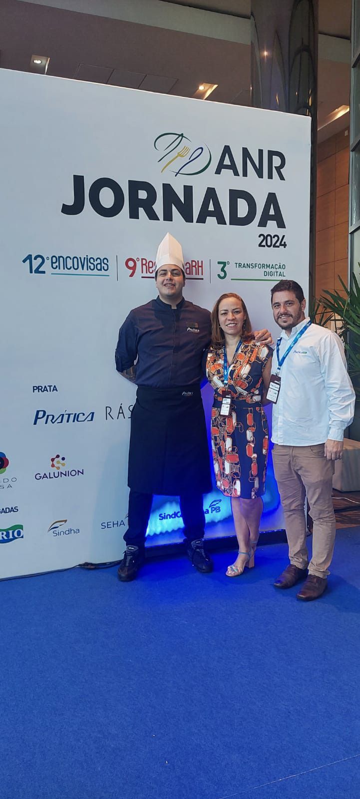 Um grupo de pessoas está posando para uma foto em frente a uma placa que diz jornada.