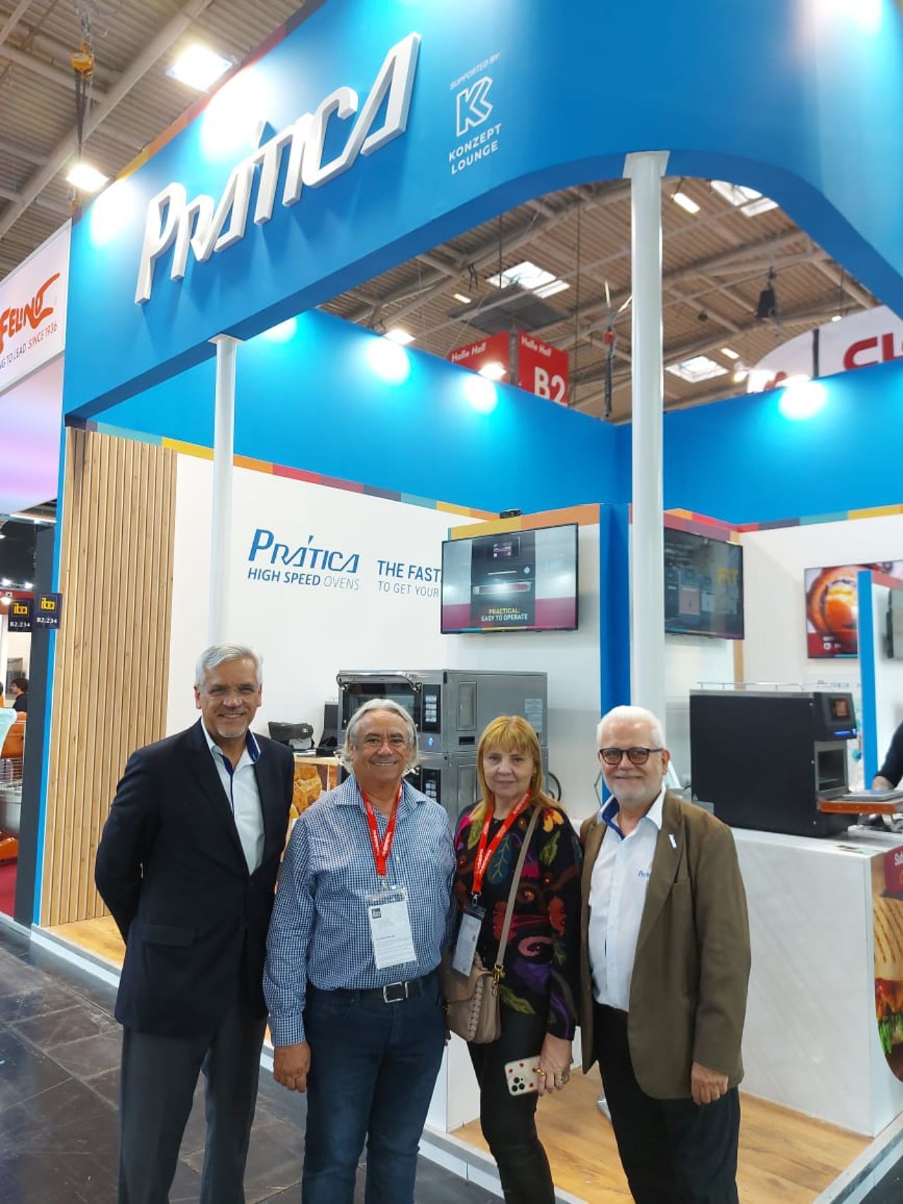 Um grupo de pessoas está posando para uma foto em frente a uma placa que diz prima