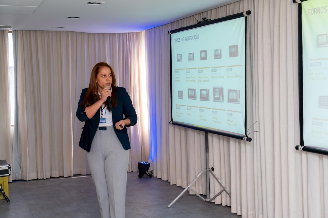 Uma mulher está fazendo uma apresentação em frente a uma tela de projetor.