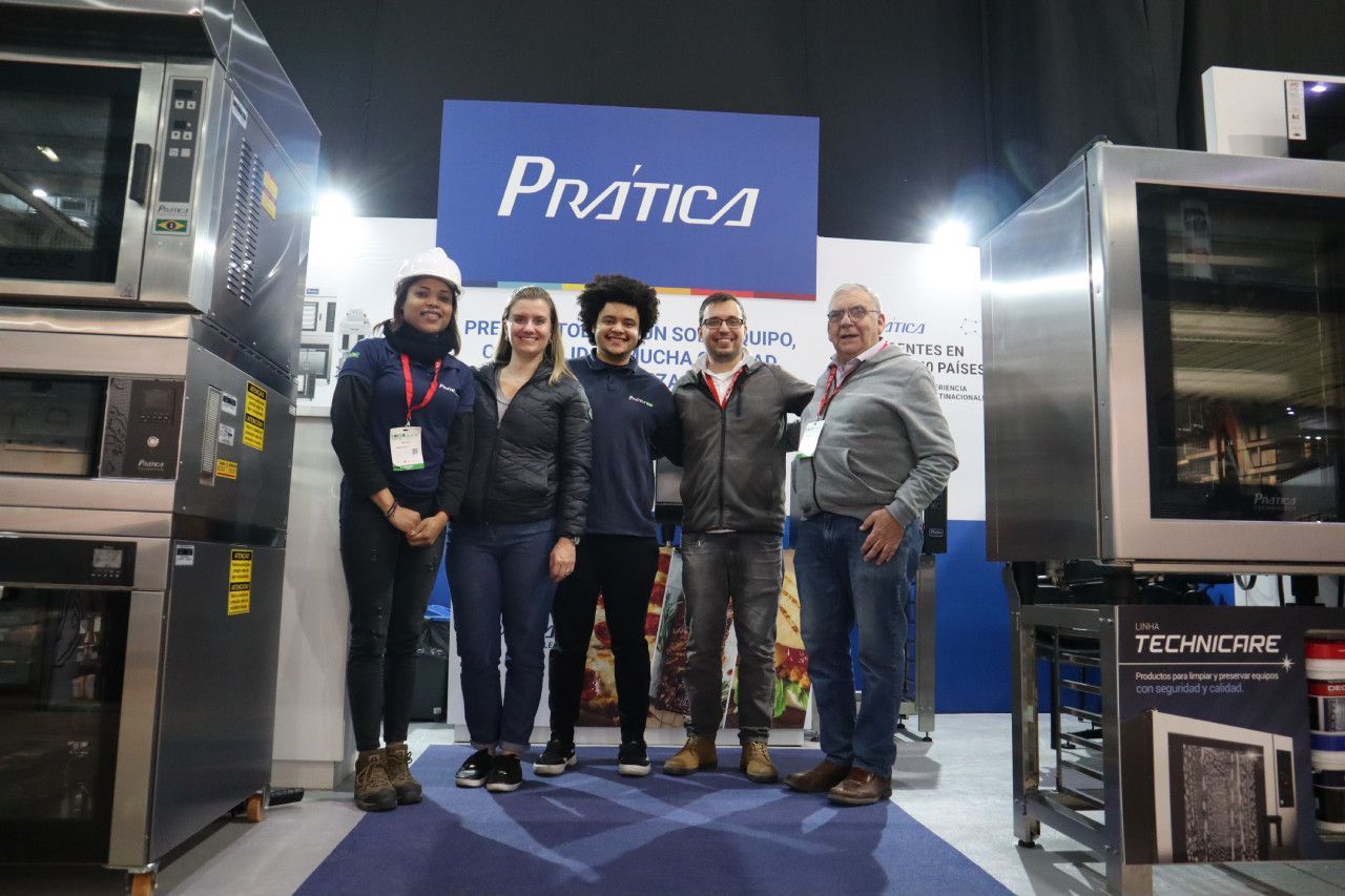 Um grupo de pessoas está posando para uma foto em frente a uma placa de prática.