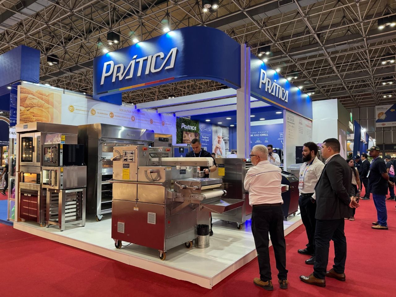 Um grupo de pessoas está em volta de um estande em uma convenção.