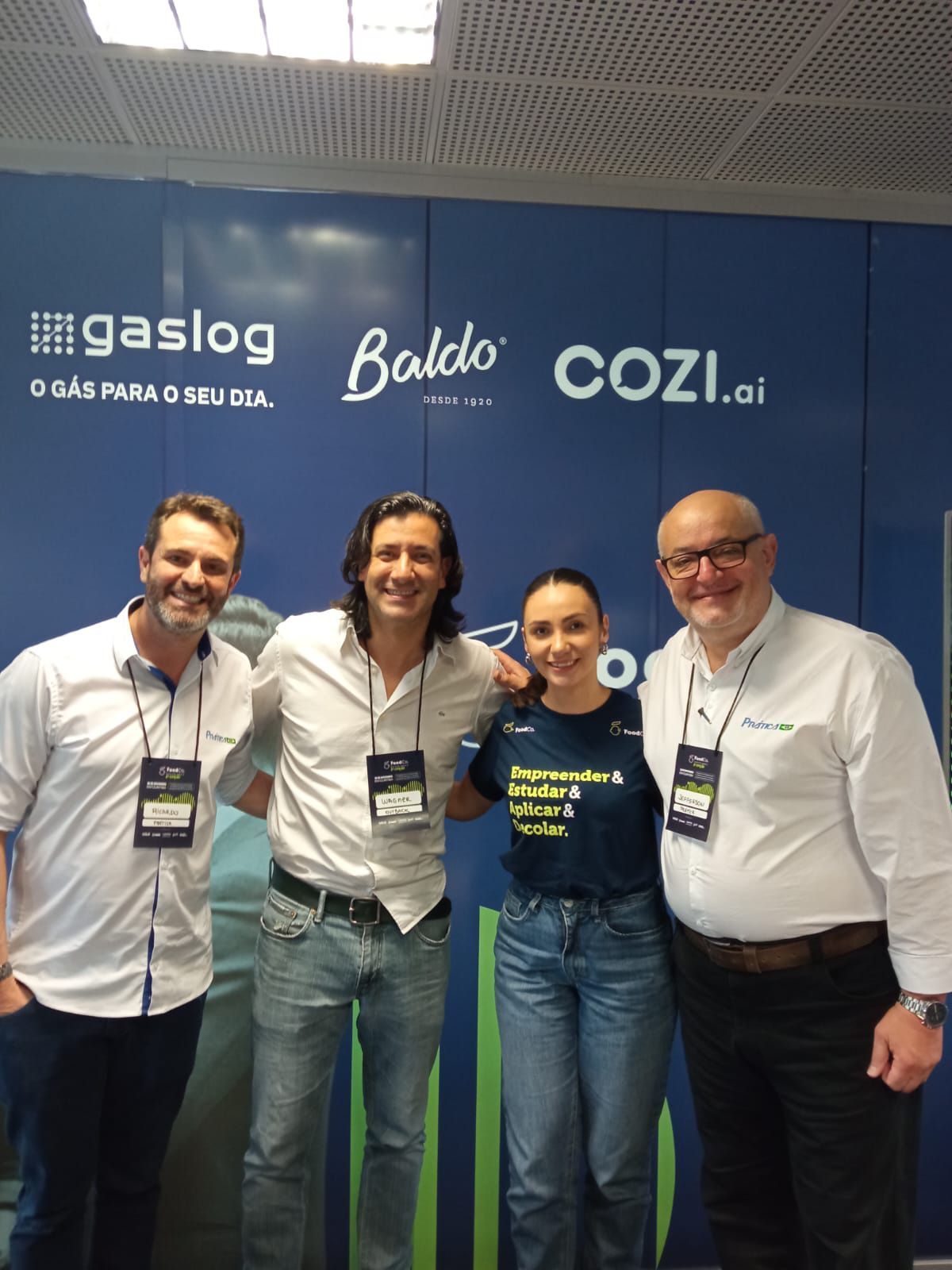 Um grupo de pessoas posando para uma foto em frente a uma parede azul.