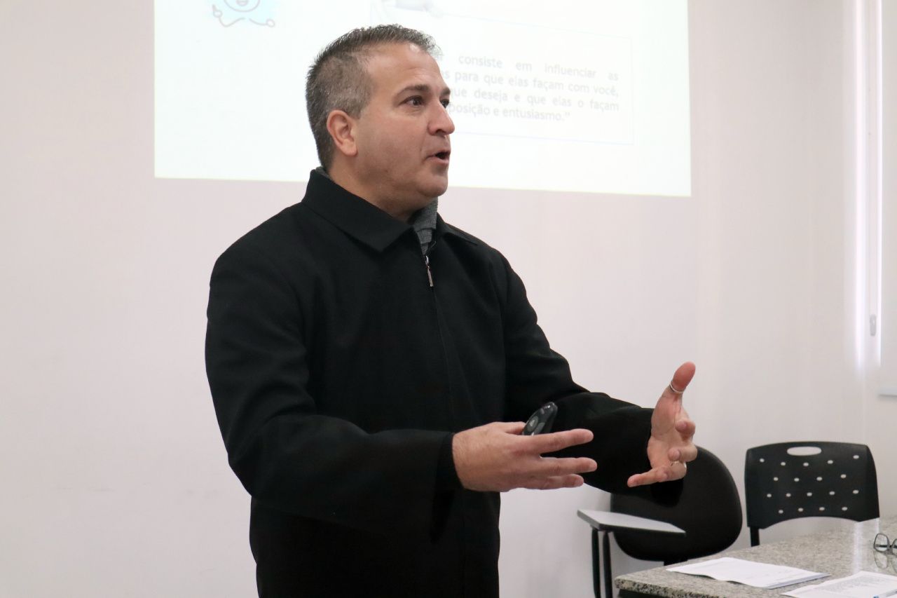 Um homem de jaqueta preta está fazendo uma apresentação