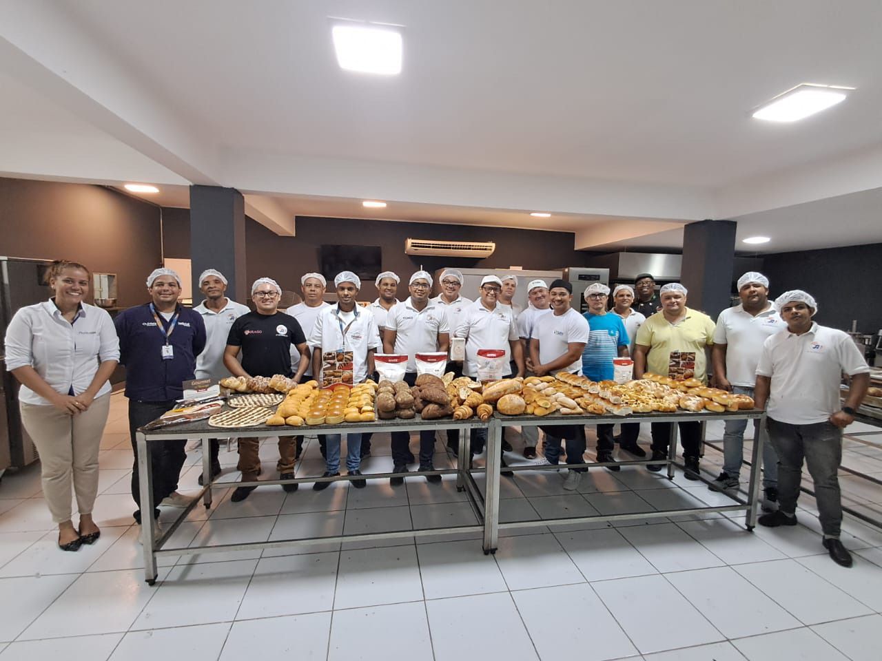 Um grupo de pessoas está de pé ao redor de uma mesa com pão sobre ela.