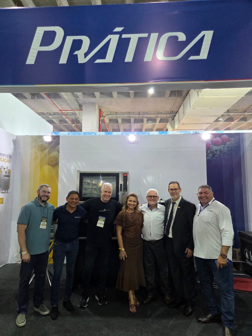 Grupo de pessoas posando em frente a uma placa azul 