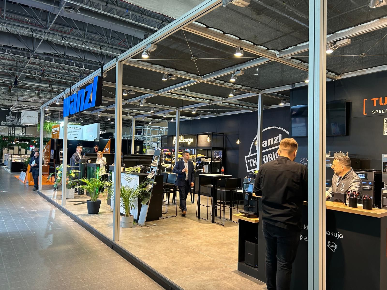 Um homem está parado em frente a um estande em uma convenção.