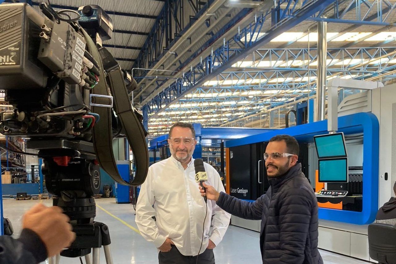 Um homem está sendo entrevistado por um cinegrafista em uma fábrica.